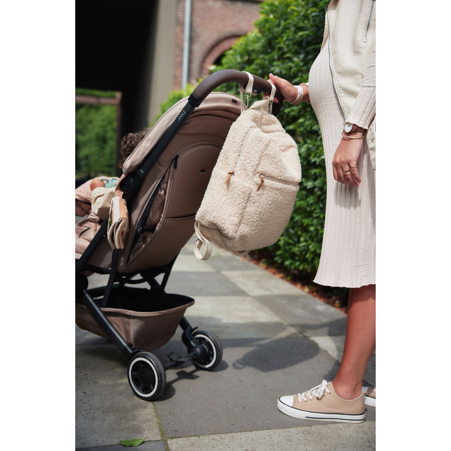 Wickeltasche Rucksack Beige in Teddy Optik hängt am Kinderwagen