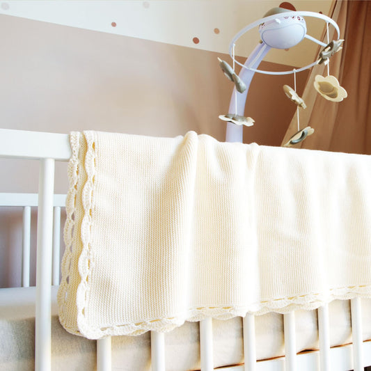 Babydecke Weiß hängt über Babybett