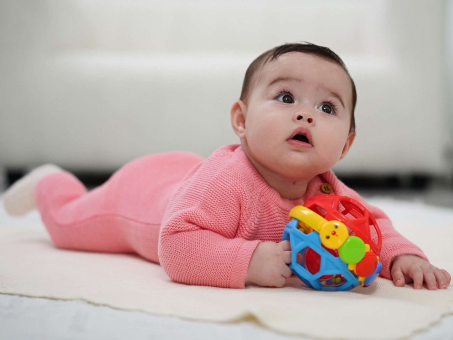 Baby im rosa Strampler aus Baumwolle von der Seite