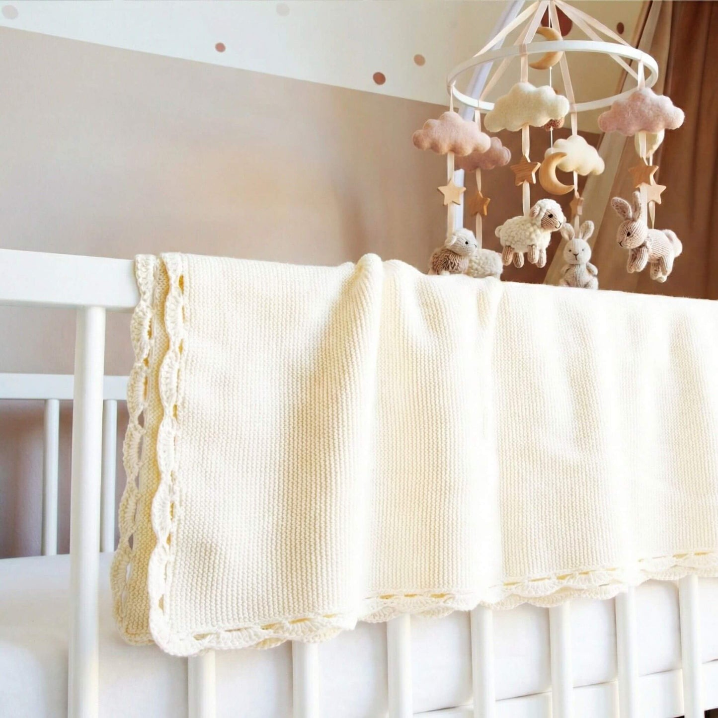 Babydecke in beige hängt über dem Babybettchen