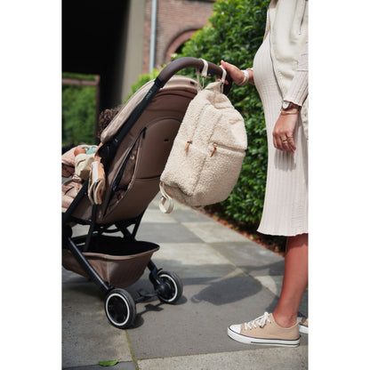 Wickeltasche Rucksack Beige in Teddy Optik hängt am Kinderwagen