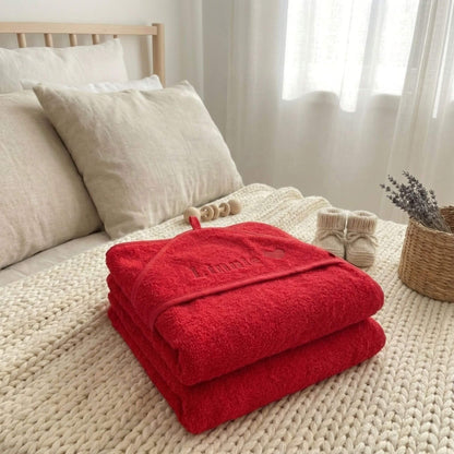 Zwei rote Geburtshandtücher liegen gestapelt auf dem Bett