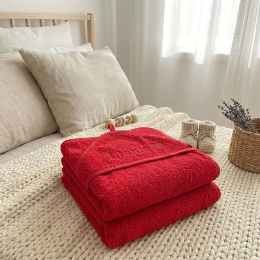Zwei rote Geburtshandtücher liegen gestapelt auf dem Bett